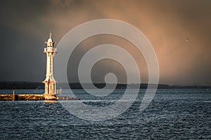 View of lighthouse on Lake Geneva with storm clouds in background.