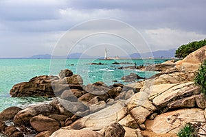 View of the lighthouse in the sea near the rocky shore. Heavenly Grottoes Park, Sanya, China