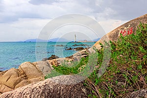 View of the lighthouse in the sea near the rocky shore. Heavenly Grottoes Park, Sanya, China