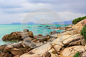 View of the lighthouse in the sea near the rocky shore. Heavenly Grottoes Park, Sanya, China