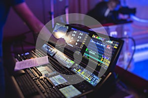 View of lighting technician operator working on mixing console workplace during live event concert on stage show broadcast, light