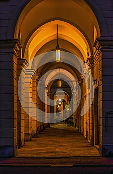 A view through a lit collonade at night in La Spezia, Italy