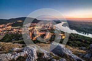 View of Lit Small City with River from the Hill at Sunset