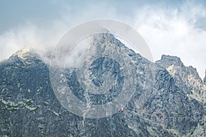 Pohľad na Lomnický štít, známy skalnatý vrchol vo Vysokých Tatrách na Slovensku. Zamračený veterný deň.