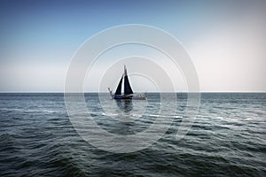 View of a lonely sailing ship with black sail, sailing on the turbulent barges of a Dutch lake