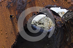 View looking through a dangerously discarded boiler drum at the Victorian brickworks at Porth Wen, Isle of Anglesey