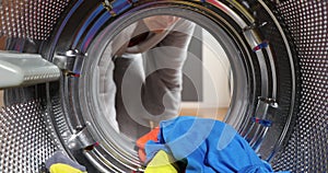 View looking out from inside washing machine filled with laundry. Loading colored clothes and linen in washing machine. Doing