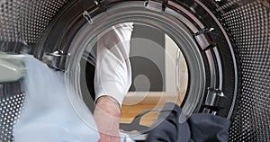 View looking out from inside washing machine filled with laundry. Loading colored clothes and linen in washing machine. Doing