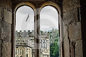 View looking out of a medieval, stonework window to a distant tower