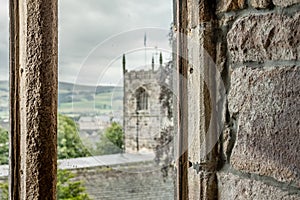 View looking out of a medieval, stonework window to a distant tower