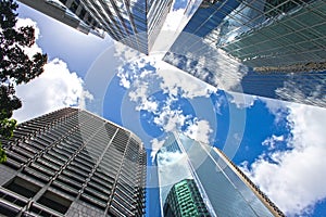 View looking up at blue cloudy sky through skyscrapers reflecting clouds and other buildings in CBD Brisbane Queensland Australia