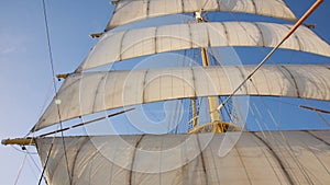 A view looking upwards at the mast, blown sails and rigging of a Big Sailing Ship. Vertical perspective.
