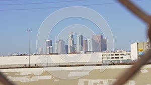 View of Los Angeles downtown skyline through chain link fence on blue sky summer day in slow motion