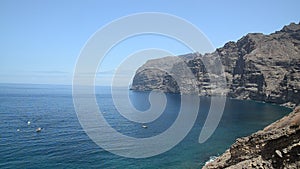 View of Los Gigantes cliffs.White boat is sailing on ocean.Holiday mood, willingness to travel again.