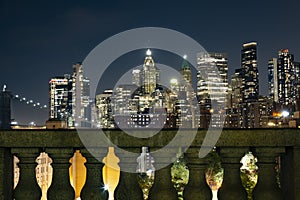 View of lower Manhattan and Financial district at night. Skyscrapers with lights on in New York City seen above columns of