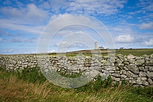 View of Lundy lighthouse with a wall in the foreground.