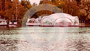 View of the luxurious white tent and gazebo for ceremonies and celebrations on the shore pier on a summer evening