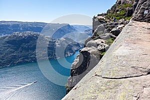 View at Lysefjord and huge Preikestolen cliff on Kjerag mountain. Passenger ship floats from Lysebotn village. Visitors hike to Pu