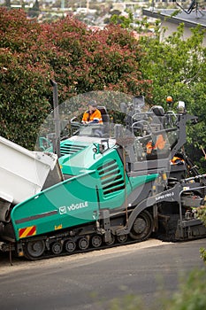 View of machinery and workers laying new bitumen on a suburban road near Hobart