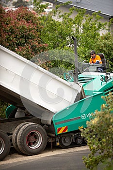 View of machinery and workers laying new bitumen on a suburban road near Hobart