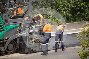 View of machinery and workers laying new bitumen on a suburban road near Hobart