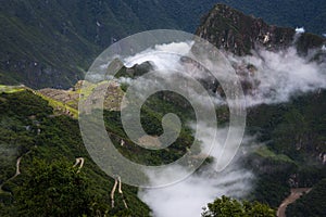 View of Machu Picchu surrounded by clouds from the Sun Gate and the Urubamba River, in Peru
