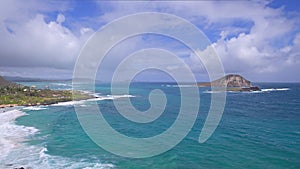 View of Makapuu beach. Waves of Pacific Ocean wash over yellow sand of tropical beach. Magnificent mountains of Hawaiian