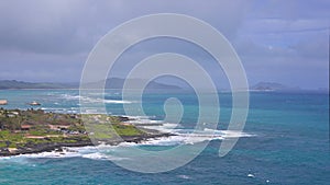 View of Makapuu beach. Waves of Pacific Ocean wash over yellow sand of tropical beach. Magnificent mountains of Hawaiian