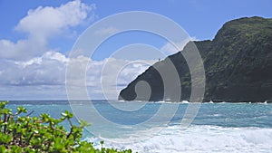 View of makapuu lighthouse. Waves of Pacific Ocean wash over yellow sand of tropical beach. Magnificent mountains of