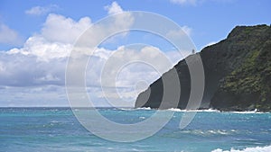 View of makapuu lighthouse. Waves of Pacific Ocean wash over yellow sand of tropical beach. Magnificent mountains of