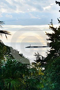 A view at Malaga lighthouse through palm tree brancheBeautiful sunset view and the sea and the lighthouse through the branches of