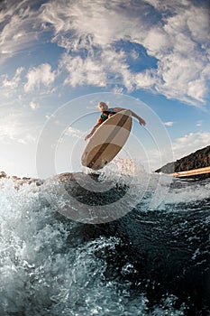 view of male wakeboarder while skilfully jumping over splashing wave