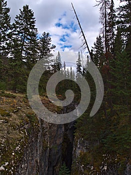 View of Maligne Canyon with narrow ravine between forest on cloudy day in autumn in Jasper National Park, Alberta, Canada.