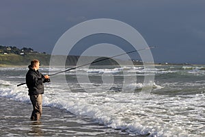 View of man fishing from beach at Harlech, Wales
