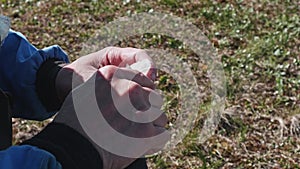 View of man hands. Man cuts candle using knife. He sits on ground. Man hobby.