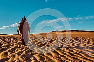 View of a man in local dress walking on a yellow sand dune