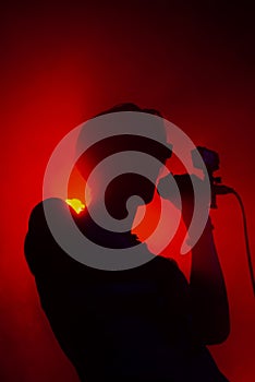 View on man with microphone on stage in red lights