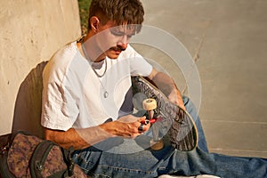 View of a man repairing his skateboard in the skate park. Extreme sport concept