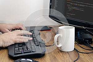 View of a man`s hands typing on his pc or computer keyboard at his home desk while working. Work at home concept