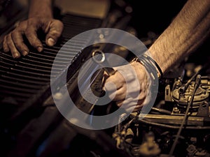 View of a man& x27;s strong hands with leather bracelets fixing the gear of a machine