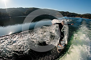view of man wakesurfer energetically balancing on the splashing wave