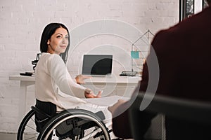 View of manager giving documents to disabled businesswoman in office