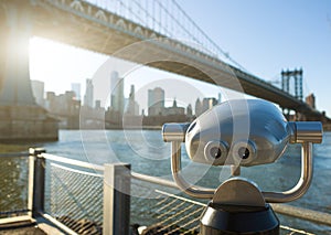 View of Manhattan bridge and New York City with a coin operated telescope binoculars viewer for tourists