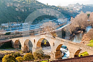 View of Manresa town old bridge, symbol of medieval architecture of the small catalan town, during sunny winter day with yellow