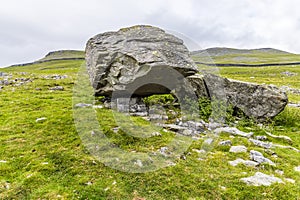 A view of a masive glacial erratic boulder resting on limestone pavement on the southern slopes of Ingleborough, Yorkshire, UK