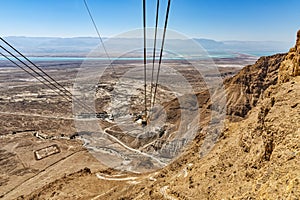 View from the Massada mountain, over the landscape around the Dead Sea, the parking lot for buses, the paths down and the cables o