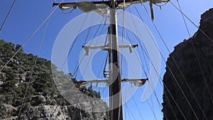 View of the mast of yacht sailing among mountain cliffs