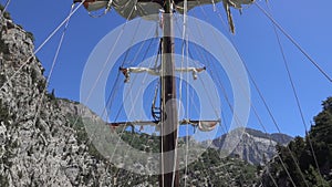 View of the mast of yacht sailing among mountain cliffs