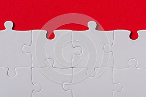 View of matched white jigsaw puzzle pieces isolated on red