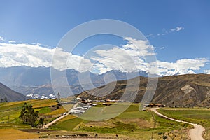 View of the meadow, hills, blue sky with clouds, some trees and some country houses, located in Tambillo